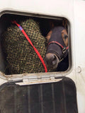 Horse in trailer eating from an EcoNets hay net with red seam