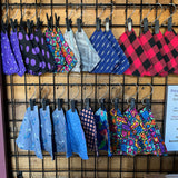 dog bandanas in many prints, lined up in 2 rows and clipped to a display rack