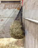 Half bale 1.5" EcoNets hay net hanging in a box stall