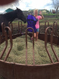 woman standing on hay bale with an EcoNets round bale net in a red feeder