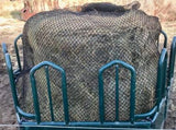 EZ Feeder hay net kit over a round bale and attached to a large green metal feeder