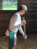 woman cleaning a stall wearing a Teal HH around her waist